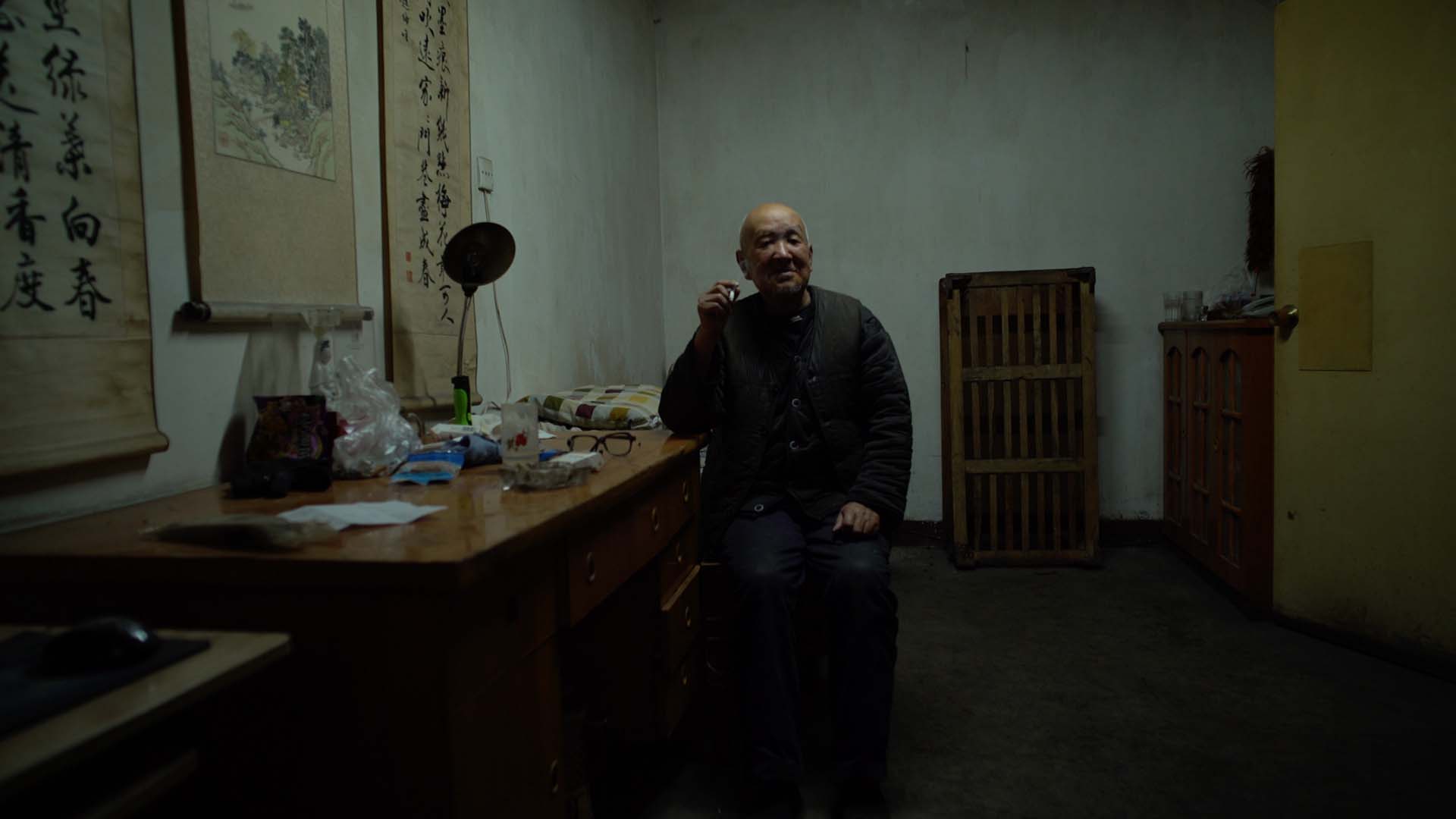 An old man in Dead Souls is sitting in a relatively dark room