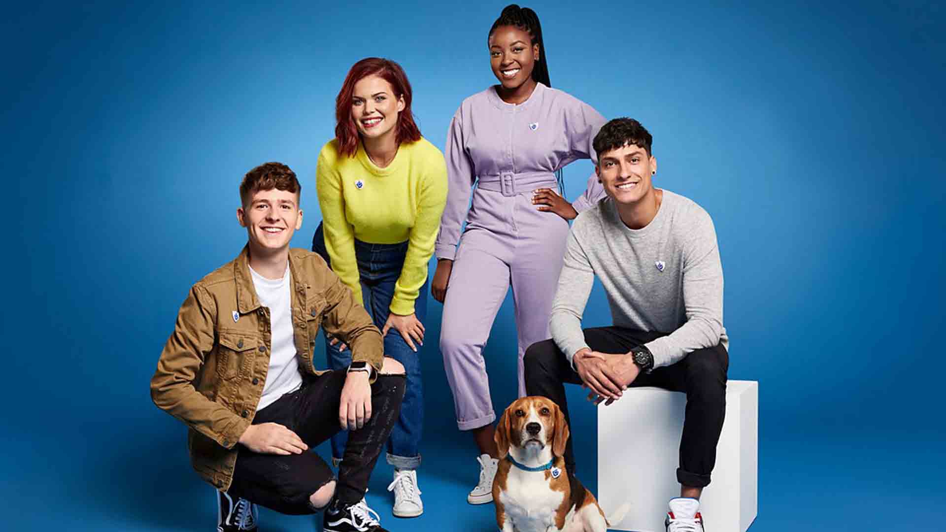 The hosts of the series Blue Peter next to a pet dog