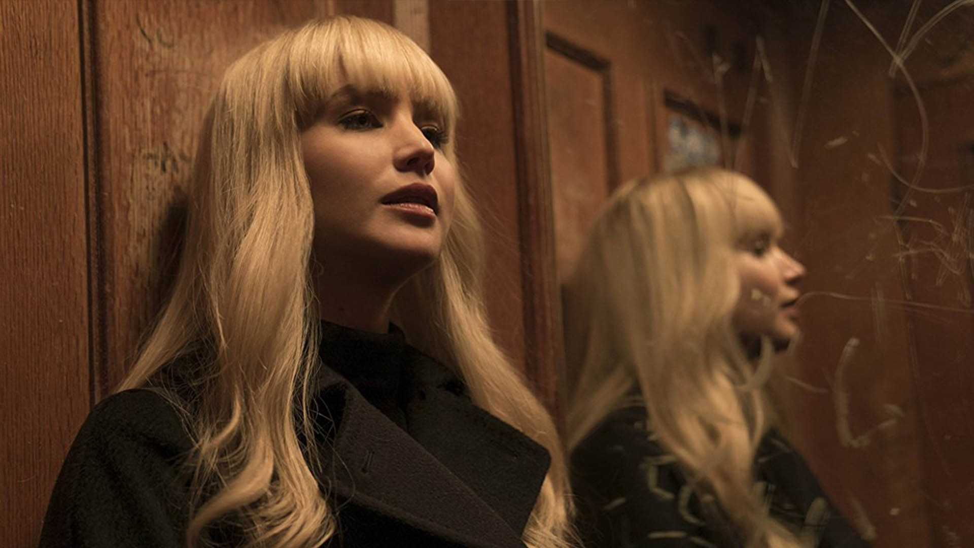 Jennifer Lawrence stands next to a mirror in Red Sparrow