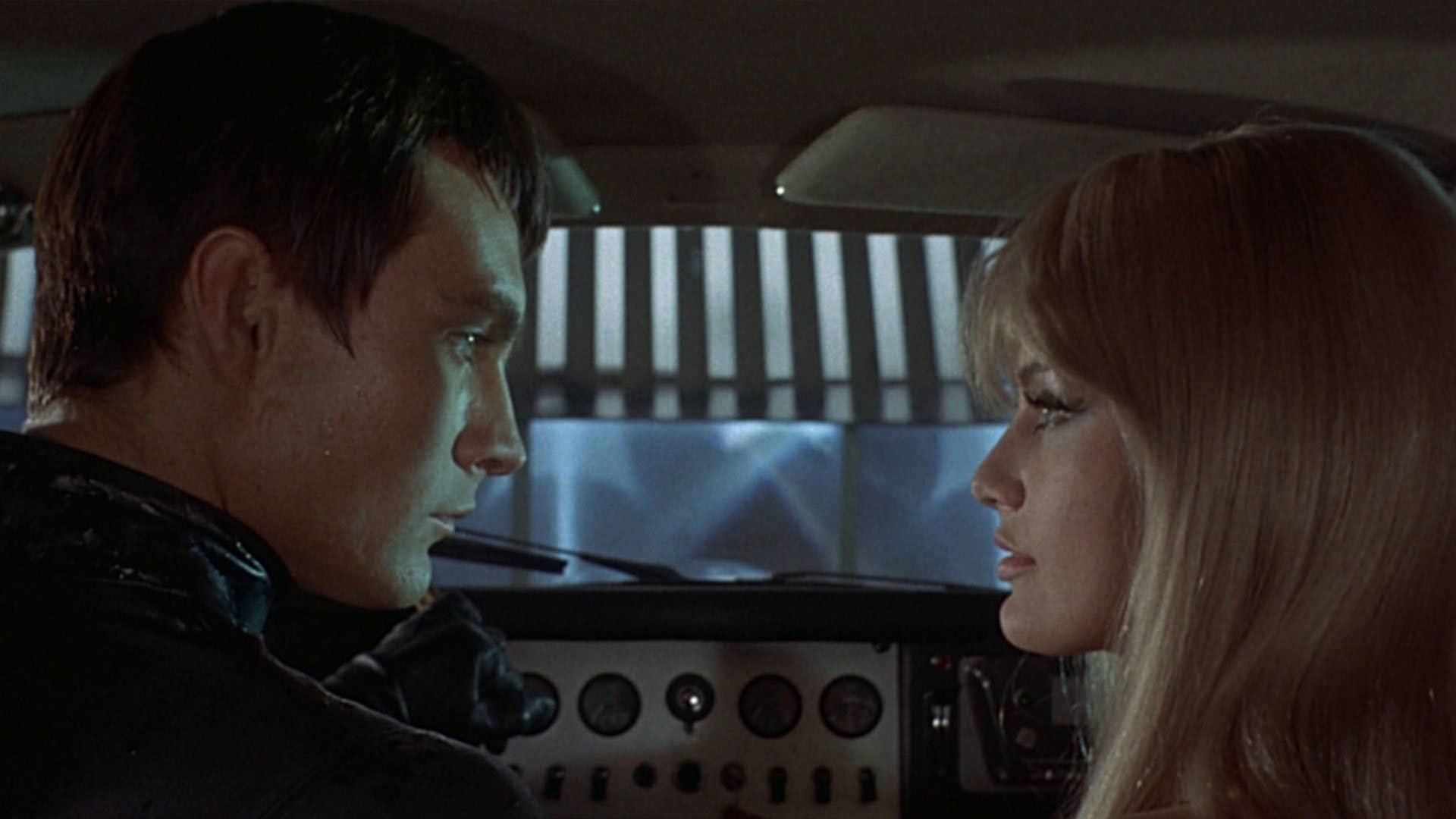 John Philip Love and Marissa Mel look at each other in the car in Danger: Diabolik