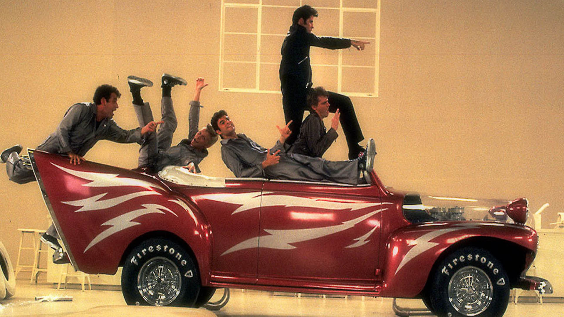 John Travolta and other Grease cast on a car