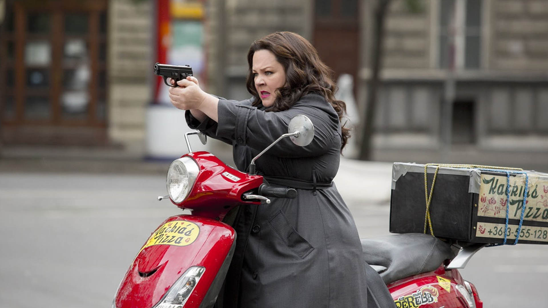 Melissa McCarthy with a motorcycle and a small gun in the movie Spy