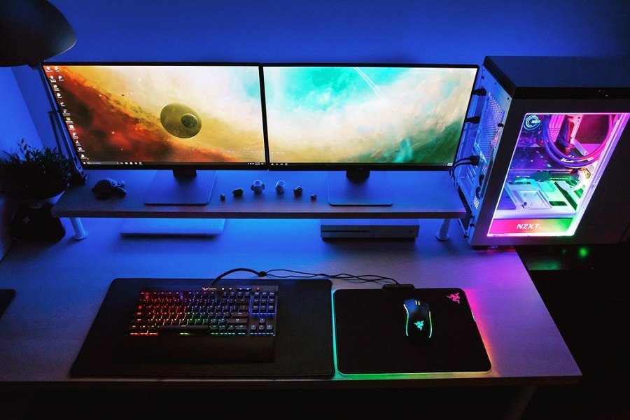 A gaming computer with two gaming monitors and a RGB color keyboard and mouse