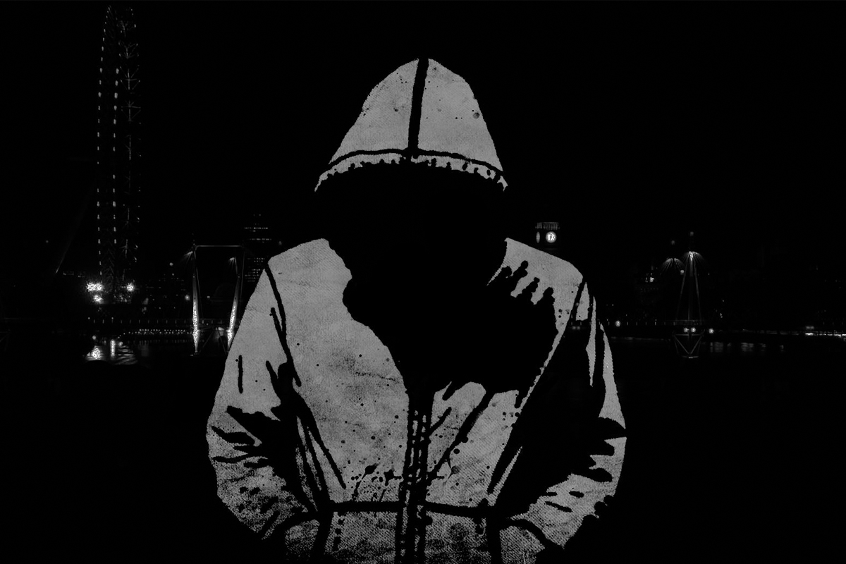 Unknown hacker in a hoodie standing with his head down with his hands in his pockets